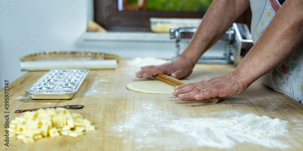 Close-up of woman's hands working the dough to prepare cheese ravioli. Traditional Sardinian cuisine. Homemade.