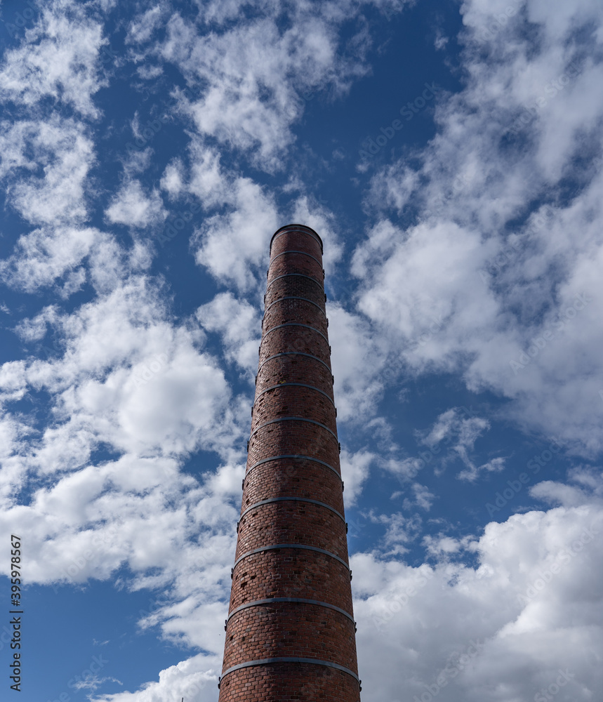 Tall chimney on a bright sunny day with clouds seen from the earth