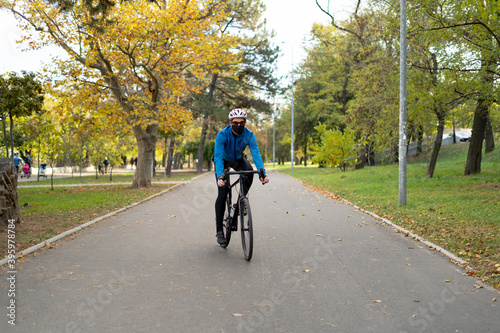 Wallpaper Mural Portrait of a young sporty man in a mask who rides a bicycle through the park on a bicycle road. He has a safety helmet and jacket. Torontodigital.ca