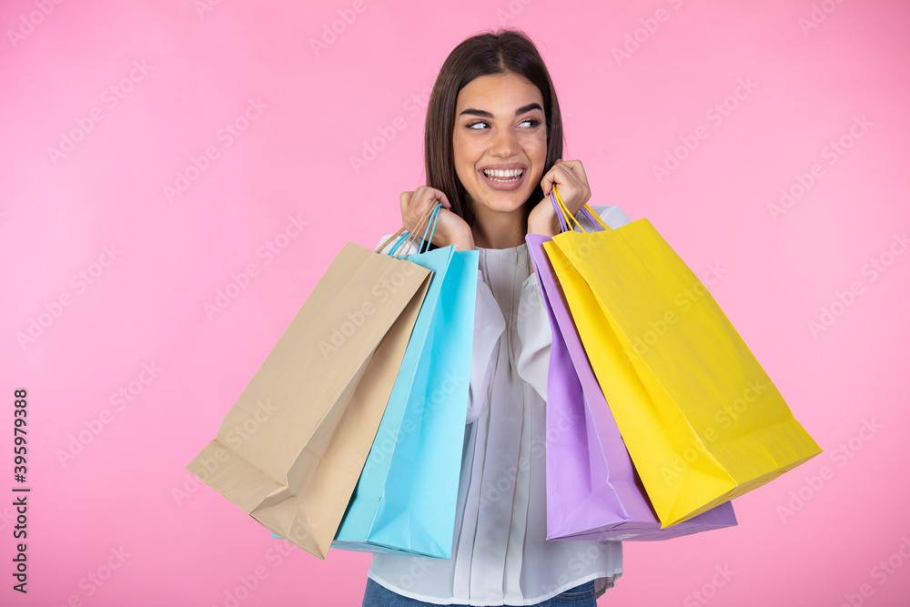 Cheerful young woman holds bags with a purchases. Joyful trendy girl with a colorful shopping bags. Model holding bags with gifts. Happy caucasian woman. Shopping, sales, black friday concept.