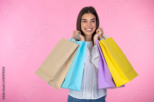 Studio portrait of a beautiful young woman, in a white outfit, holding in her hands a few shopping bags. she is laughing and looking very happy. Shopping woman holding shopping bags 