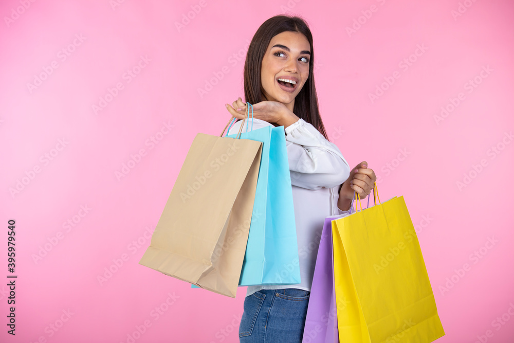 Pleasant woman enjoying shopping. Amazing brunette girl posing with shopping bags. Shopping woman happy smiling holding shopping bags isolated on pink background