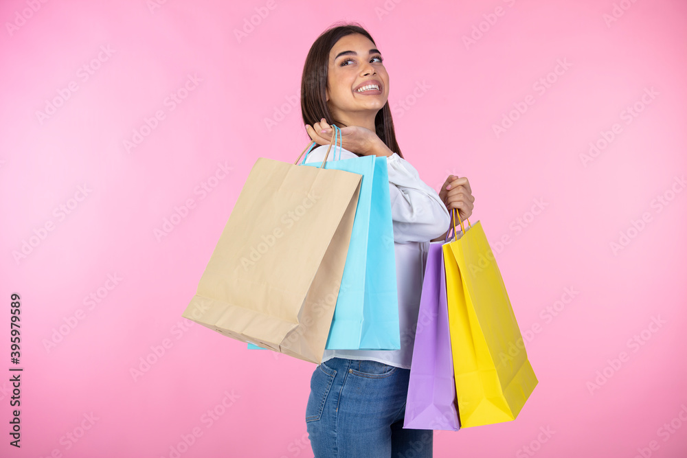Amazing brunette girl posing with shopping bags. Shopping woman happy smiling holding shopping bags isolated on pink background. Shopping, sales, black friday concept.