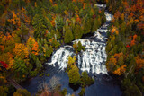 Beautiful travel photograph of Bond Falls waterfall on the Middle Branch Ontonagon River surrounded by evergreen and deciduous trees with autumn colored foliage in Upper Michigan.