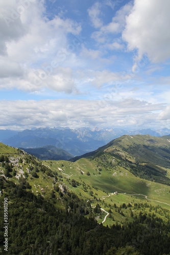 view of the mountains and valleys  green  covered with vegetation and the road between the hills  with a blue sky and clouds