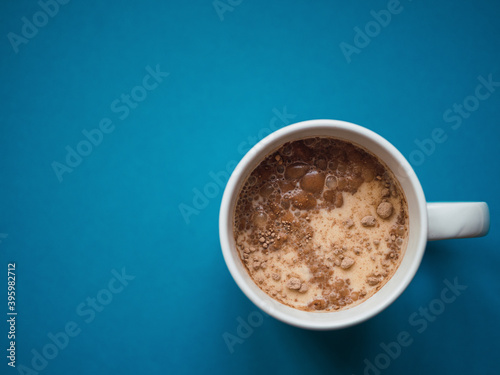 Top view a white mug with blue background. Copy space. Breakfast concept