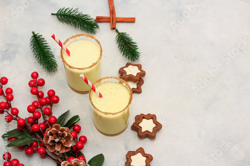 Classic winter Christmas drink egnog in two glasses with chocolate chip cookies and decoration on a concrete background photo