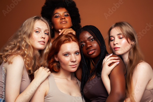 young pretty caucasian, afro, scandinavian woman posing cheerful together on brown background, lifestyle diverse nationality people concept