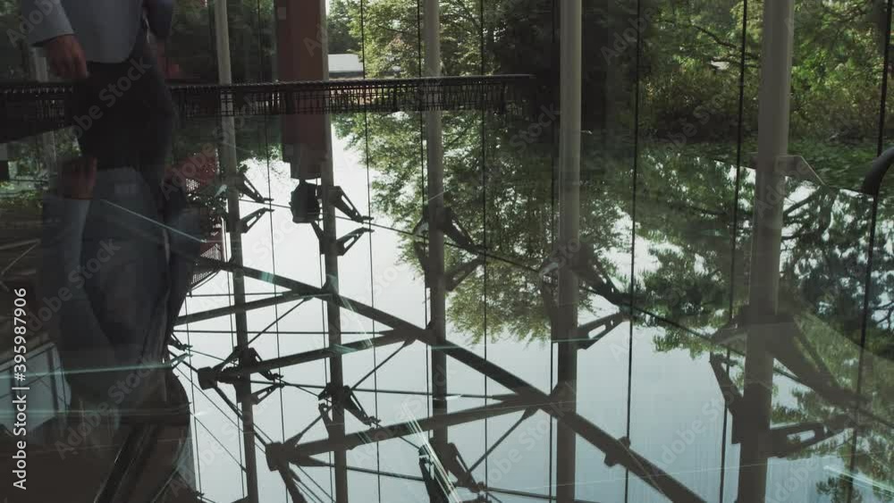 A young handsome man in an architect or lawyer suit walks around a modern office. Reflection in a glass table. A young handsome man in an architect or lawyer suit walks around a modern office. Reflection in a glass table.