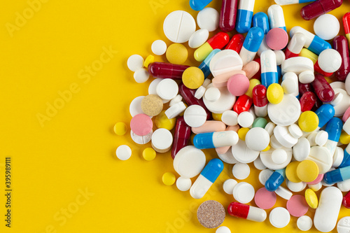 Many different pills on a yellow background. Medical concept. Concept of threat of various diseases. Top view.