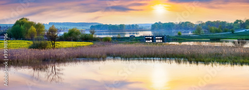 Fototapeta Naklejka Na Ścianę i Meble -  Spring landscape with river and picturesque sky reflected in water, sunset on the river, panorama