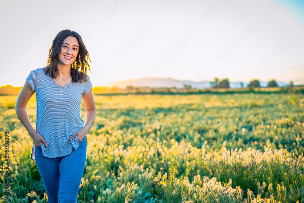 Portrait of a smiling Happy woman walking among the wild flowers in a large field on a summer evening. Portrait of a smiling Happy woman walking among the wild flowers in a large field on a summer evening.
