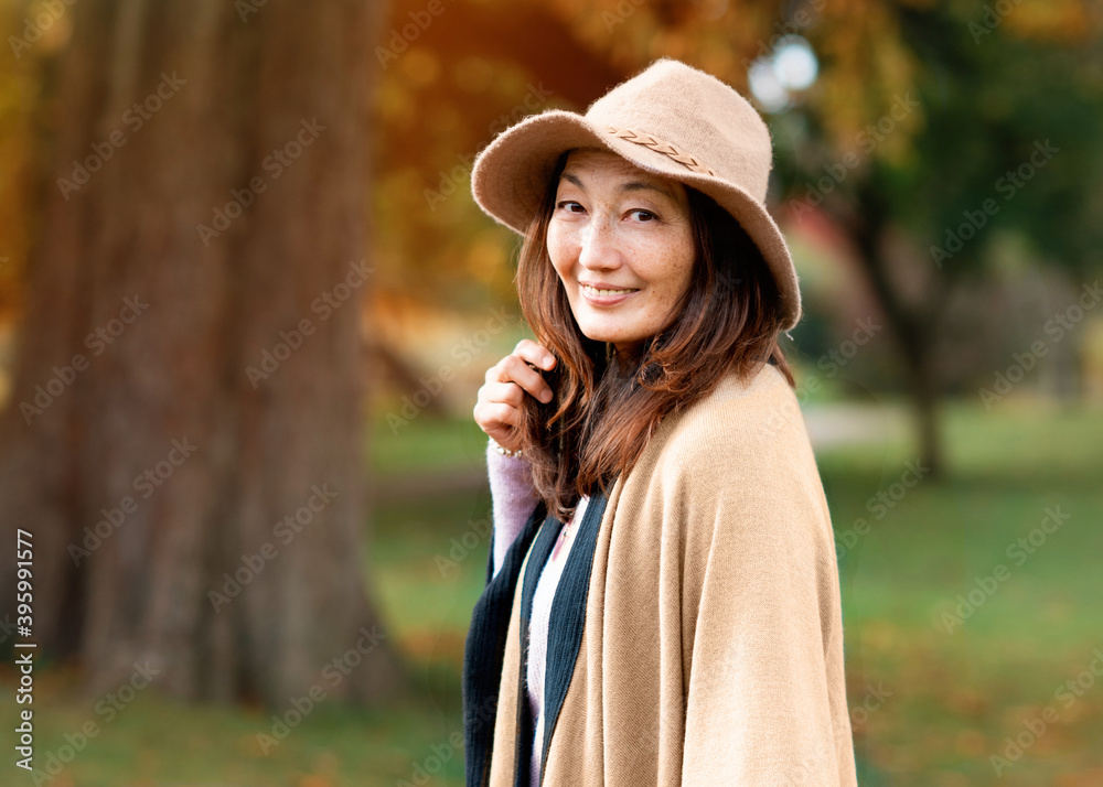 asian woman in a hat walking in the autumn park