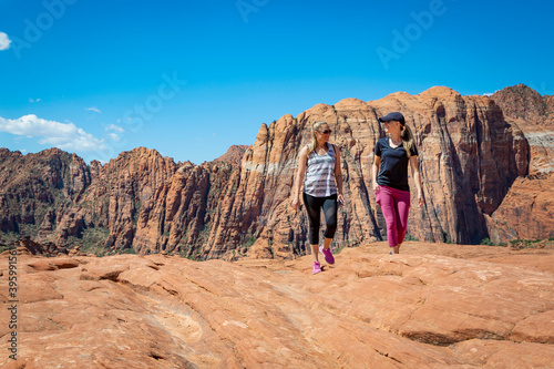 Two athletic women hiking together on a scenic trail in Snow Canyon Park Utah USA. Overlooking some amazing rock formations in southern Utah