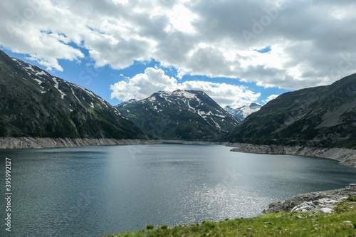 Fototapeta Naklejka Na Ścianę i Meble -  Dam in Austrian Alps. The artificial lake stretches over a vast territory, shining with navy blue color. The dam is surrounded by high mountains. In the back there is a glacier. Controlling the nature