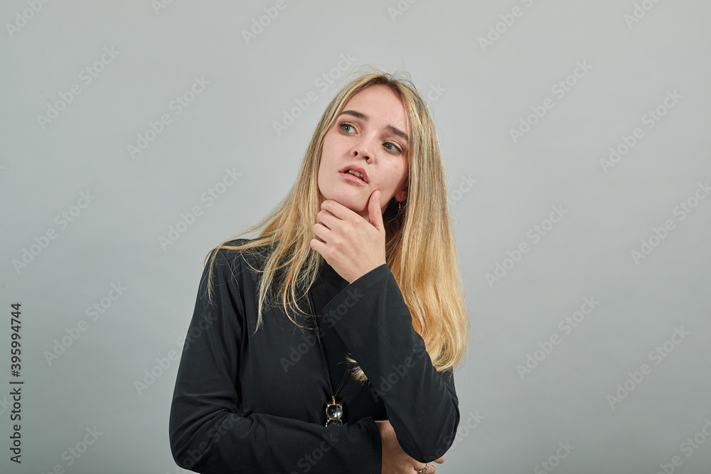 Hand on chin thinking about question, pensive expression. Doubt. Thoughtful face. Using that incredibly sharp business mind. Young attractive woman, dressed black sweater with green eyes, blonde hair Hand on chin thinking about question, pensive expression. Doubt. Thoughtful face. Using that incredibly sharp business mind. Young attractive woman, dressed black sweater with green eyes, blonde hair
