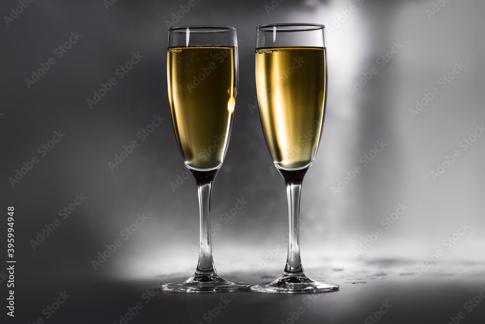 Two glasses with golden champagne on a sparkling metal background. Two glasses with golden champagne on a sparkling metal background.