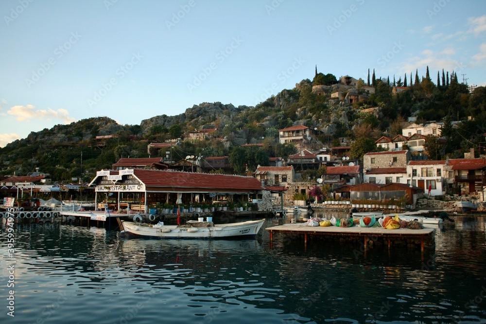 Boats, touristic fish restaurants and ancient stone houses on the shore of the river and lake of ataturk dam. 