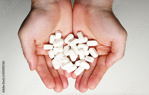 A pile of white pills in a male hand. A man holds pills in his hand. The concept of medicine, illness, health.