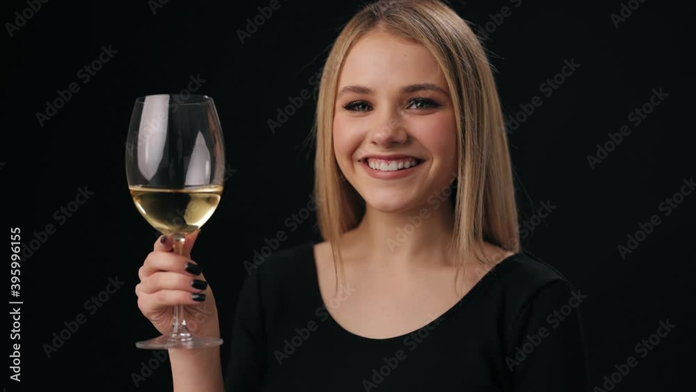 Beautiful woman with blond hair holding glass filled with white wine. Isolated over black background. Concept of celebration and alcoholic drink. Beautiful woman with blond hair holding glass filled with white wine. Isolated over black background. Concept of celebration and alcoholic drink.