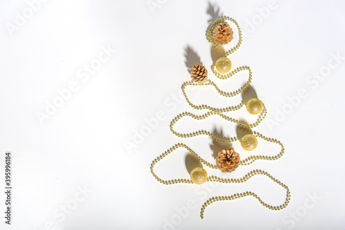 Christmas composition. Christmas tree made of gold bead garland with decorations on white background. © Екатерина Спиридонов
