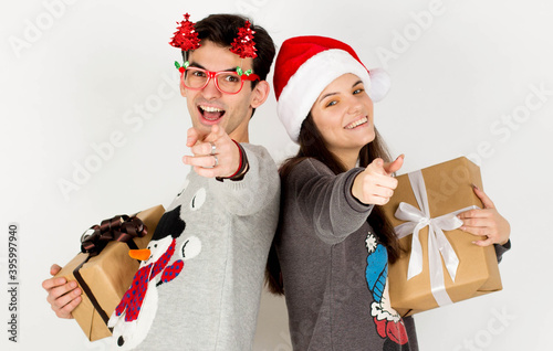 Young couple guy girl in Christmas sweater Santa hat posing isolated on white wall background. New Year celebration party concept. Mock up copy space