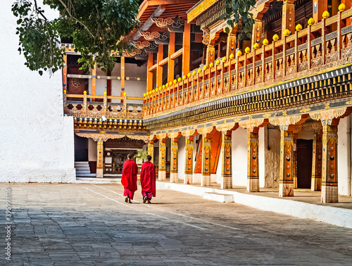 Two Buddhist monks in their traditional red dress walking in the monastery Punakha Dzong courtyard, Bhutan. photo