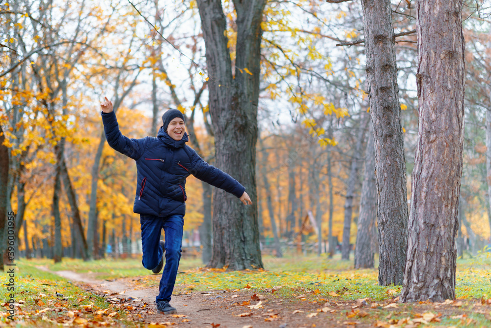 a boy running through the park and enjoys autumn, beautiful nature with yellow leaves a boy running through the park and enjoys autumn, beautiful nature with yellow leaves