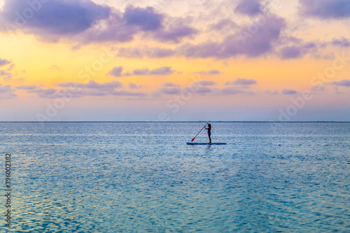 A girl silhouette on a stand up puddleboard on stunning colorful sea sunset background © Денис Ржанов