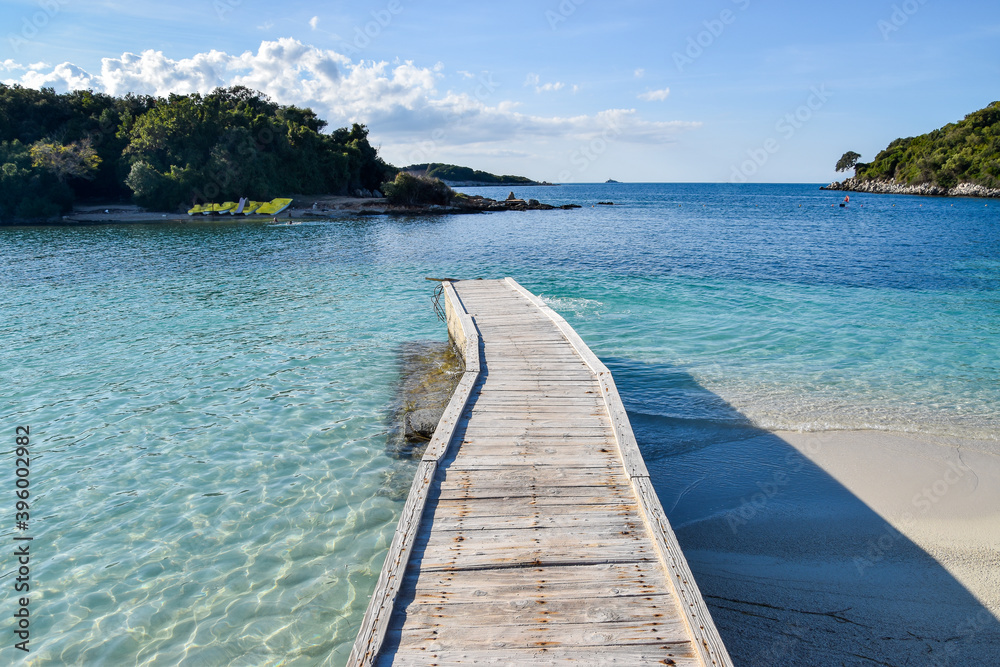 Wooden small bridge and crystal blue sea water. Sunny day at sea. Beautiful beach without visitors.