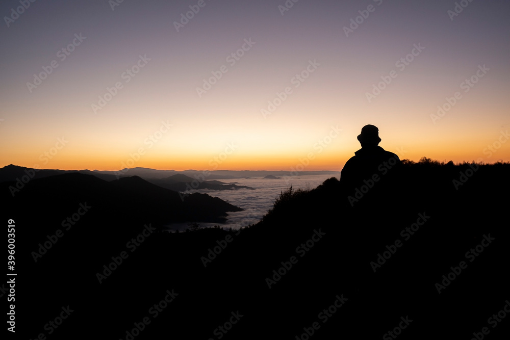 traveler looking at the fog cloud on the high hill at sunset