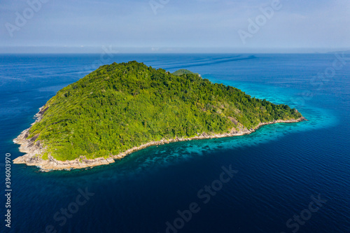 Fototapeta Naklejka Na Ścianę i Meble -  Aerial view of a beautiful tropical island full of jungle and beach, surrounded by coral reef