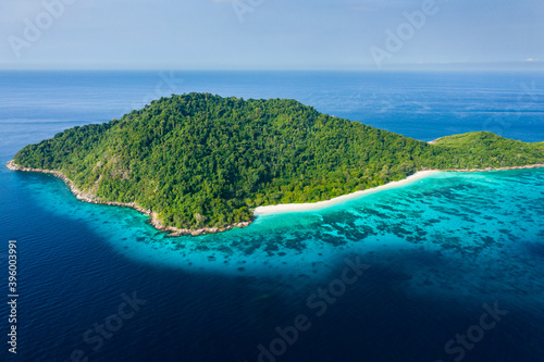 Aerial view of an empty beach on a beautiful tropical island surrounded by clear water and a coral reef