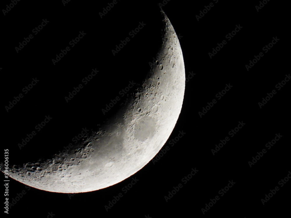 Young growing moon close up against the black sky
