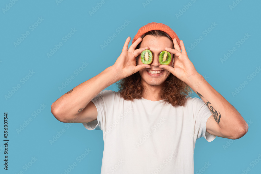 Young adult guy covered eyes with kiwi fruit Young adult guy covered eyes with kiwi fruit