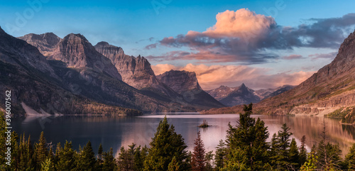 Beautiful Panoramic View of a Glacier Lake with American Rocky Mountain Landscape in the background. Dramatic Colorful Sunrise Sky. Taken in Glacier National Park, Montana, United States. photo
