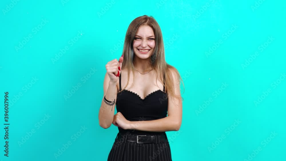 Shy and harmless woman prays holding hands together. Charming girl, dressed in black T-shirt with cleavage, in the studio on a blue background. female casting for TV commercial, student portrait Shy and harmless woman prays holding hands together. Charming girl, dressed in black T-shirt with cleavage, in the studio on a blue background. female casting for TV commercial, student portrait