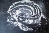 on a black background flour is scattered in the form of a circle and a spiral, background image