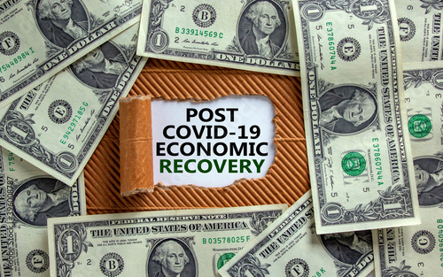 Post covid-19 recovery. The words 'post covid-19 economic recovery' appearing behind torn brown paper. Dollar bills. Business and post covid-19 pandemic concept.