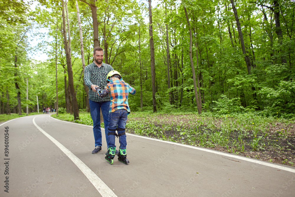 Father and son in the open air, preparing for roller skating. Father's Day.