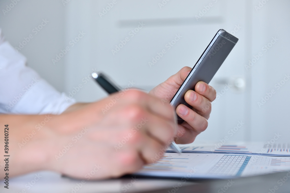 Fototapeta premium Accountant checks business report on mobile phone.