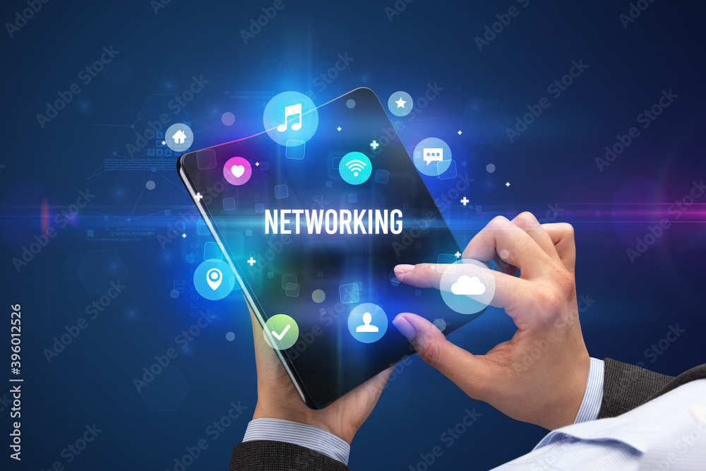Businessman holding a foldable smartphone with NETWORKING inscription, social media concept Businessman holding a foldable smartphone with NETWORKING inscription, social media concept