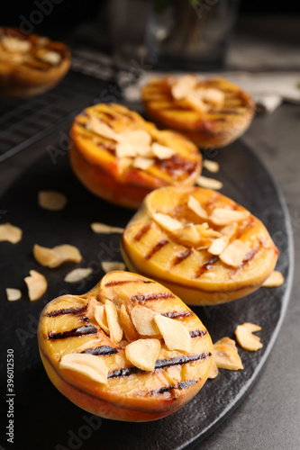 Delicious grilled peaches with almond flakes on grey table, closeup