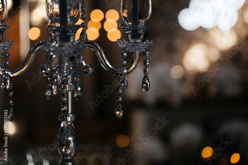 Close up glass candlestick on the dark blurred background with the place for your text. Wedding restaurant decorations. Wedding banquet. 