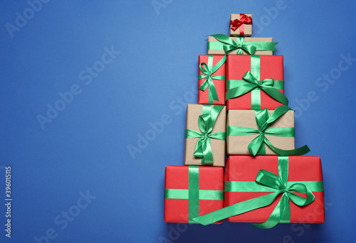 Christmas tree shape of gift boxes on blue background, flat lay. Space for text
