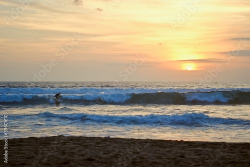 Surfer at sunset. Legian Beach, Pantai Legian, Bali, Indonesia. Bali is a popular surf spot with many surf schools. Near Kuta and Seminyak. 