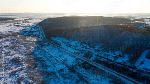 Snow-capped hills and road at sunset background photographed from drone