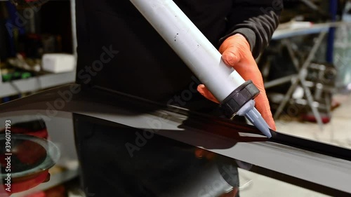 Glazier applying rubber sealing to windshield in garage, close up. High quality 4k footage