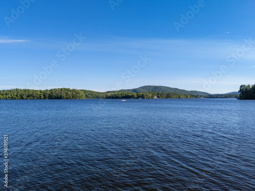 Small boat on Canada lake view with forest and mountains at edge of lake in summer