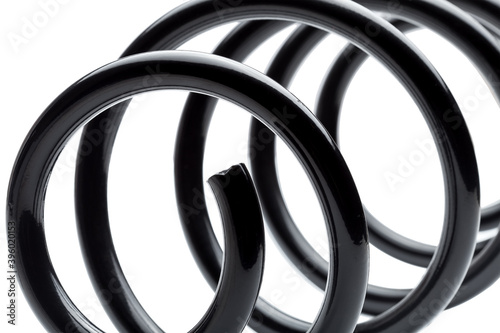 coil spring in black steel car suspension system spare parts, close up replacement part isolated on white background.